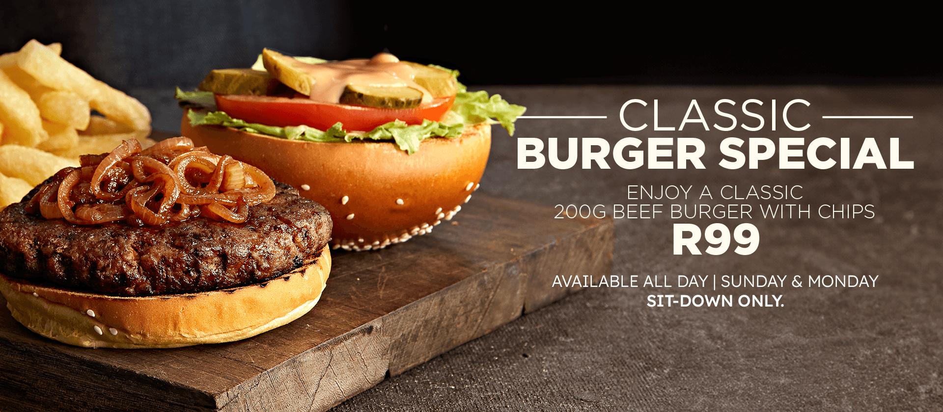 Promotional restaurant banner featuring a classic beef burger topped with caramelized onions, lettuce, tomato, pickles, and sauce, served with chips on a rustic wooden board